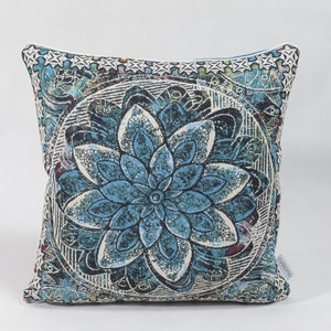 Puede incluir: Una almohada cuadrada azul y blanca con un gran dise&ntilde;o de mandala floral intrincado.