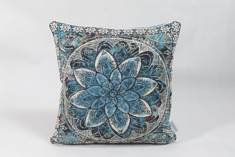Puede incluir: Una almohada cuadrada azul y blanca con un gran dise&ntilde;o de mandala floral intrincado.