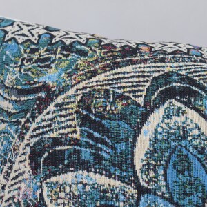 Puede incluir: Una almohada de tiro azul, verde y blanca con un dise&ntilde;o floral.