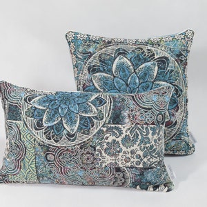Puede incluir: Dos almohadas decorativas rectangulares con un patr&oacute;n paisley azul, verde y blanco. Las almohadas son de tela suave y texturizada.