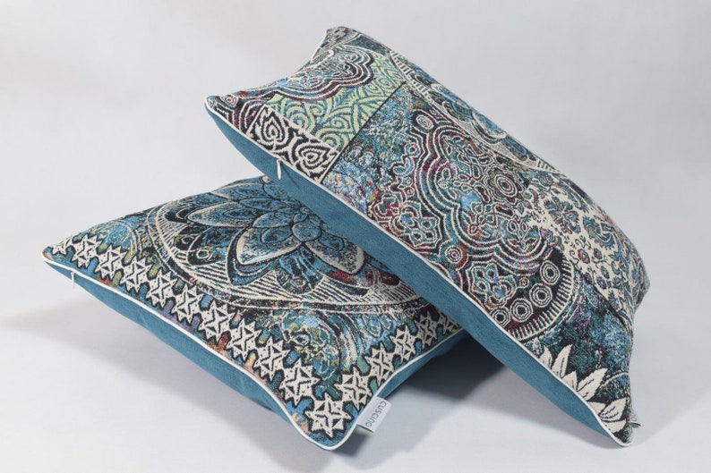 Puede incluir: Dos almohadas decorativas con un patr&oacute;n paisley azul y blanco. Las almohadas tienen un borde azul turquesa y una cremallera blanca.