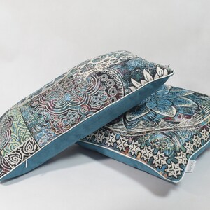 Puede incluir: Dos almohadas decorativas con un patr&oacute;n paisley azul y blanco. Las almohadas tienen un borde azul turquesa y un ribete blanco.