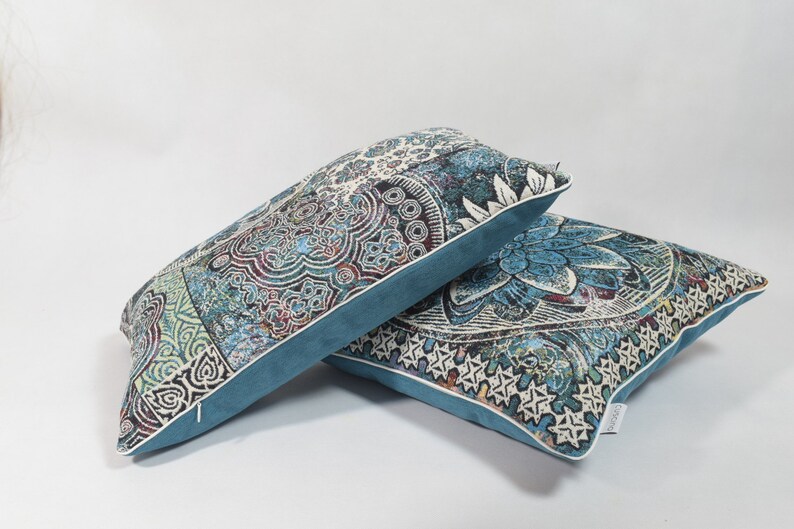 Puede incluir: Dos almohadas decorativas con un patr&oacute;n paisley azul y blanco. Las almohadas tienen un borde azul turquesa y un ribete blanco.
