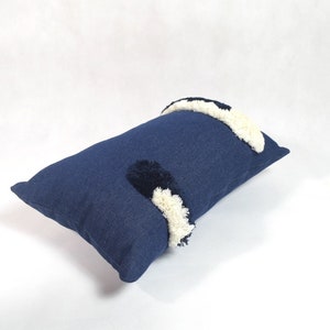 May include: A blue rectangular pillow with white and black pom-poms.