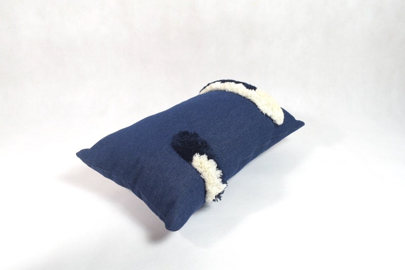 May include: A blue rectangular pillow with white and black pom-poms.