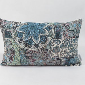 Puede incluir: Una almohada rectangular con un dise&ntilde;o estampado en azul, verde y blanco. El patr&oacute;n presenta un gran motivo floral en el centro.