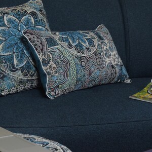 Puede incluir: Dos cojines de tiro azules y blancos con estampado sobre un sof&aacute; azul oscuro. Los cojines tienen un dise&ntilde;o floral y est&aacute;n dispuestos en un sof&aacute; con una revista y una tetera azul a un lado.