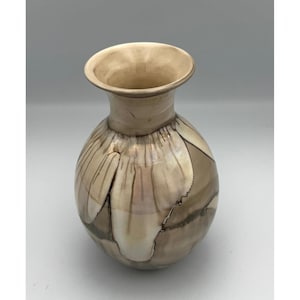 May include: A ceramic vase with a rounded body and a flared rim, featuring a glossy finish in shades of cream, beige, and dark brown with a crackled, marbled pattern that creates a distinct visual texture across the entire surface.