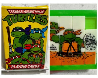 May include: A yellow box of Teenage Mutant Ninja Turtles playing cards with the turtles in green, blue, red, and purple. The image also shows a Teenage Mutant Ninja Turtles puzzle with the turtles in orange, green, and white.