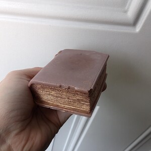 May include: A faux leather-bound book with gold-colored pages. The book is closed and has a distressed look.