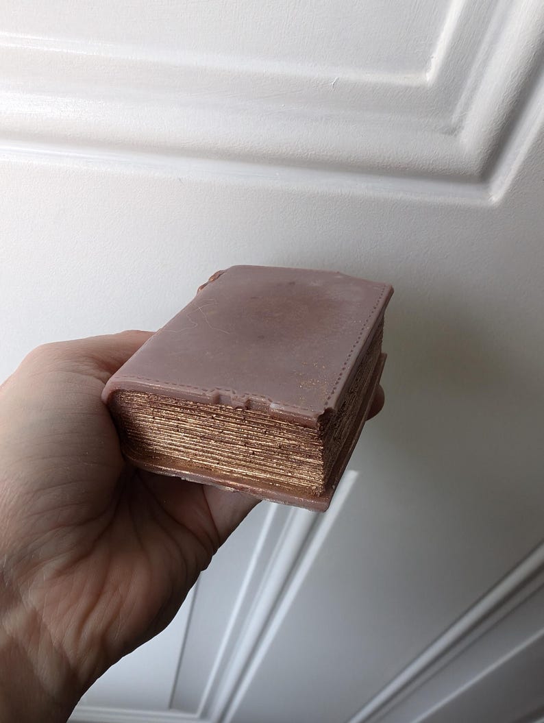 May include: A faux leather-bound book with gold-colored pages. The book is closed and has a distressed look.