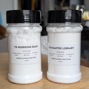 May include: Two clear plastic bottles with black lids containing white carpet dust powder. The labels read TN MORNING RAIN and ENCHANTED LIBRARY, both by BOROS CUSTOM CREATIONS, 5.5 oz, with instructions to shake, let sit for 15+ mins, and vacuum it up.