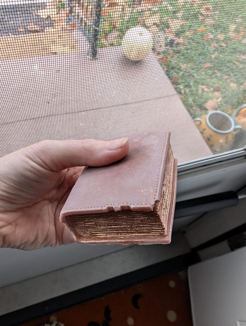 May include: A thick, brown book with gold-colored edges and a textured cover. The book is closed and appears to be very old.