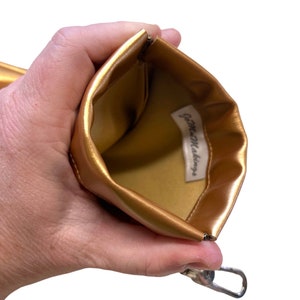 May include: Gold zippered pouch with a gold lining and the text "Game Makings" printed inside.