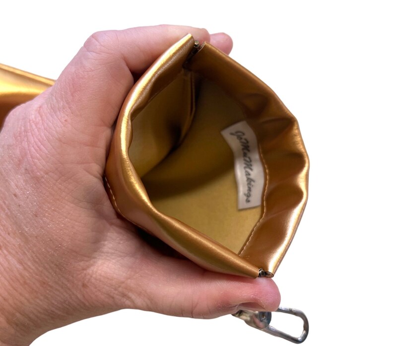 May include: Gold zippered pouch with a gold lining and the text "Game Makings" printed inside.