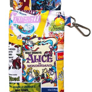 May include: A rectangular fabric pouch with a collage of vintage Disney film posters. The pouch features images from "Cinderella," "Snow White," "Alice in Wonderland," and "The Jungle Book." It has a silver clasp and a matching strap with a clip.