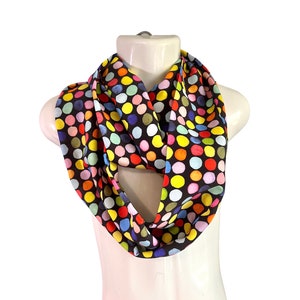 May include: A brown infinity scarf with a colourful polka dot pattern. The dots are in shades of red, yellow, blue, green, and pink.
