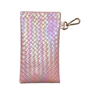 May include: A pink iridescent woven pouch with a gold zipper and a gold hook and loop closure. The pouch has a woven pattern and is perfect for storing small items.