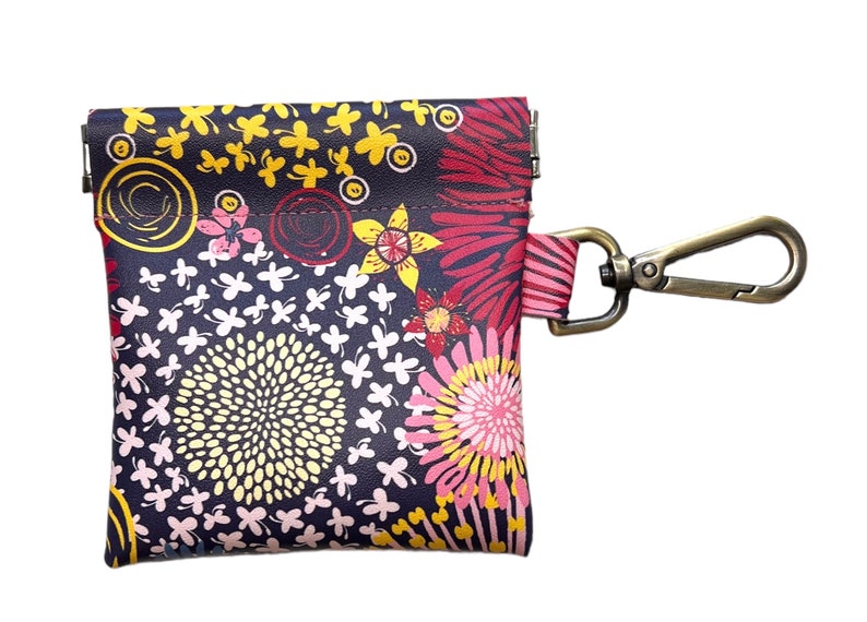 May include: A small, floral patterned pouch with a zipper closure and a metal clip. The pouch is made of a dark fabric with a variety of colorful flowers and swirls.