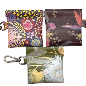 May include: Three small zippered pouches with keychains. Each pouch features a different floral print. The first pouch has a colorful floral print with pink, yellow, red, and blue flowers. The second pouch has a brown background with pink and yellow flowers. The third pouch has a green background with white and yellow flowers.