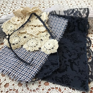 May include: A collection of fabric swatches featuring a cream-colored crochet lace piece, a black and white houndstooth patterned textile with frayed edges, a solid black fabric with a tonal floral pattern, and a black lace trim border.