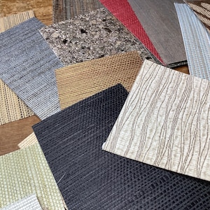 May include: A collection of various textured fabric samples in shades of beige, blue, black, and gray. The samples include woven, patterned, and solid textures, showcasing a range of materials and designs. Ideal for interior design or craft projects.