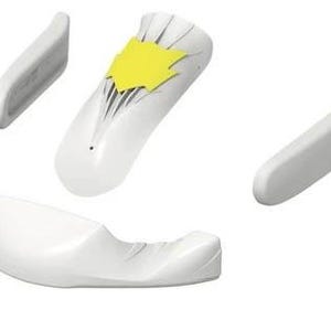 Può includere: Un insieme di componenti medici o ergonomici bianchi, tra cui una base curva, due pezzi laterali e un pezzo centrale con un accento giallo. I pezzi sono disposti su uno sfondo bianco, suggerendo un design di prodotto o un dispositivo medico.