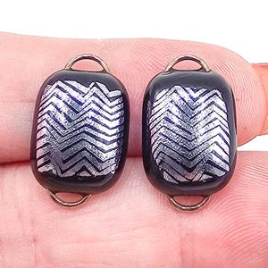 Peut inclure: Deux perles en verre bleu marine foncé de forme rectangulaire avec un motif chevron argenté métallique. Chaque perle possède une petite boucle en métal cuivré fixée en haut et en bas pour faciliter l'assemblage dans les créations.