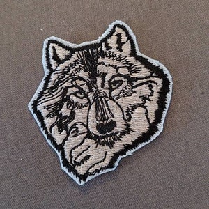 May include: A black and white embroidered wolf head patch with a light blue outline.