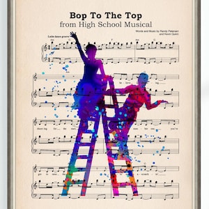 May include: A framed print featuring sheet music with the title "Bop To The Top" from High School Musical. Watercolor silhouettes of two figures on ladders are in shades of blue, purple, and red. The print has a vintage paper background.