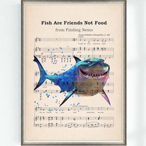 May include: Framed print featuring a watercolor illustration of a smiling shark over sheet music. The text "Fish Are Friends Not Food" and "from Finding Nemo" are at the top. The print has a vintage, whimsical aesthetic.