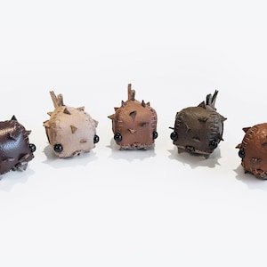 May include: Five small, handmade leather pufferfish toys in different shades of brown. Each toy has a stitched, spiky exterior and black button eyes.