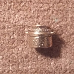 May include: Silver-toned metal thimble shaped like a small pot with a lid and two handles.