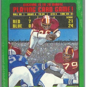 May include: A vintage box game called "All-In-The Cards Football". The box features a colorful illustration of a football game in progress. The game is designed for 15 to 20 minutes of play. The box shows the score as Red 21 and Blue 24.