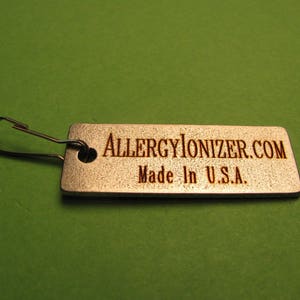 May include: A silver metal tag with a silver metal loop. The tag has the text "ALLERGYIONIZER.COM" and "Made in U.S.A." engraved on it.