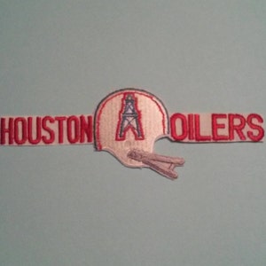May include: A white and red embroidered patch with the words "HOUSTON OILERS" and a white football helmet with a red oil derrick inside.