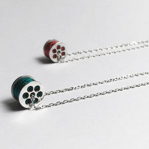May include: Two silver necklaces with a spool charm. One spool is red and the other is teal.