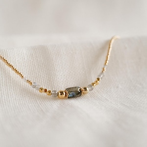 Peut inclure: Un collier délicat en or avec de petites perles et une seule pierre de labradorite rectangulaire.