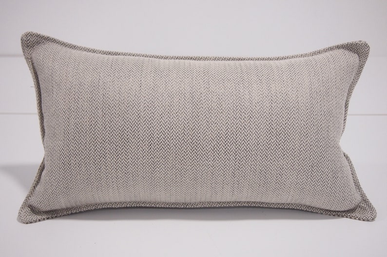 May include: A beige rectangular pillow with a subtle herringbone pattern and a white border.