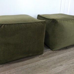 May include: Two square green velvet ottomans. The ottomans are sitting on a wood floor.