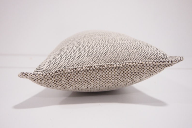 May include: A beige and brown rectangular pillow with a woven herringbone pattern.