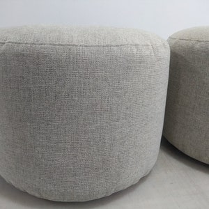 K&ouml;nnte beinhalten: Zwei runde graue Stoffhocker mit einer strukturierten Oberfl&auml;che.
