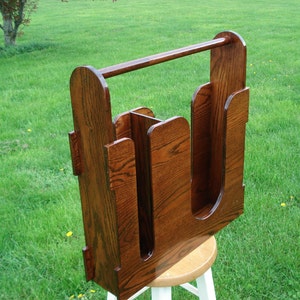 May include: A wooden boot rack with a top rail for hanging items. The rack has four compartments for storing boots and is made of dark brown wood.