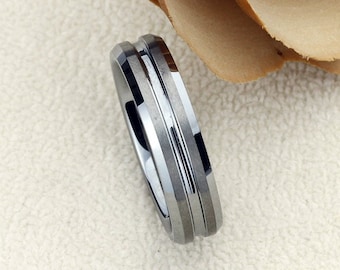 May include: A silver tungsten carbide ring with a beveled edge and three grooves.