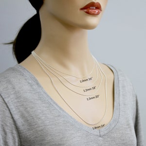 May include: Four silver chains of different lengths and thicknesses on a model's neck. The chains are labeled with their length and thickness: 1.0mm 16", 1.2mm 18", 1.5mm 20", and 1.8mm 24".
