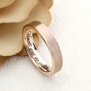May include: A rose gold wedding band with a brushed finish. The inside of the band is engraved with the text "Vinot qui se vit"