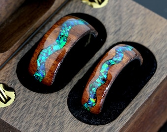 May include: Two wooden rings with a green and blue iridescent inlay. The rings are displayed in a wooden box.
