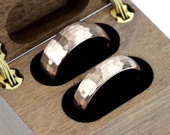 May include: Two rose gold hammered wedding bands in a wooden box.