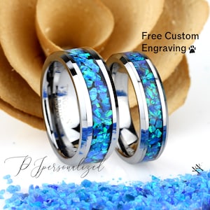 May include: Two silver tungsten carbide rings with a blue opal inlay. The rings are bevelled and have a polished finish. Free custom engraving is offered.