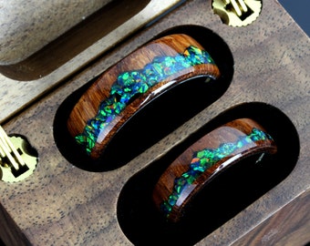May include: Two wooden rings with a green and blue opal inlay. The rings are in a wooden box with a brass latch.